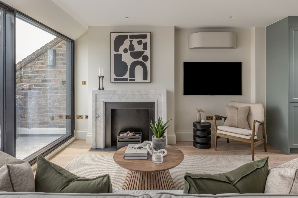 Contemporary living room in London with beige walls, light hardwood floors, a standard fireplace, a wall-mounted tv and beige floor.