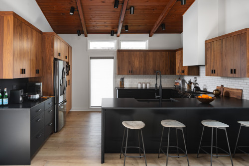 Contemporary kitchen with black island, wood kitchen cabinets, and a sloped wood ceiling.