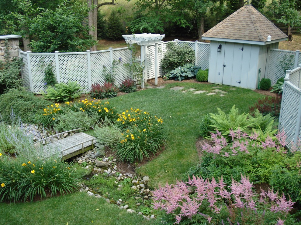 This is an example of a traditional backyard garden in Baltimore with a water feature.