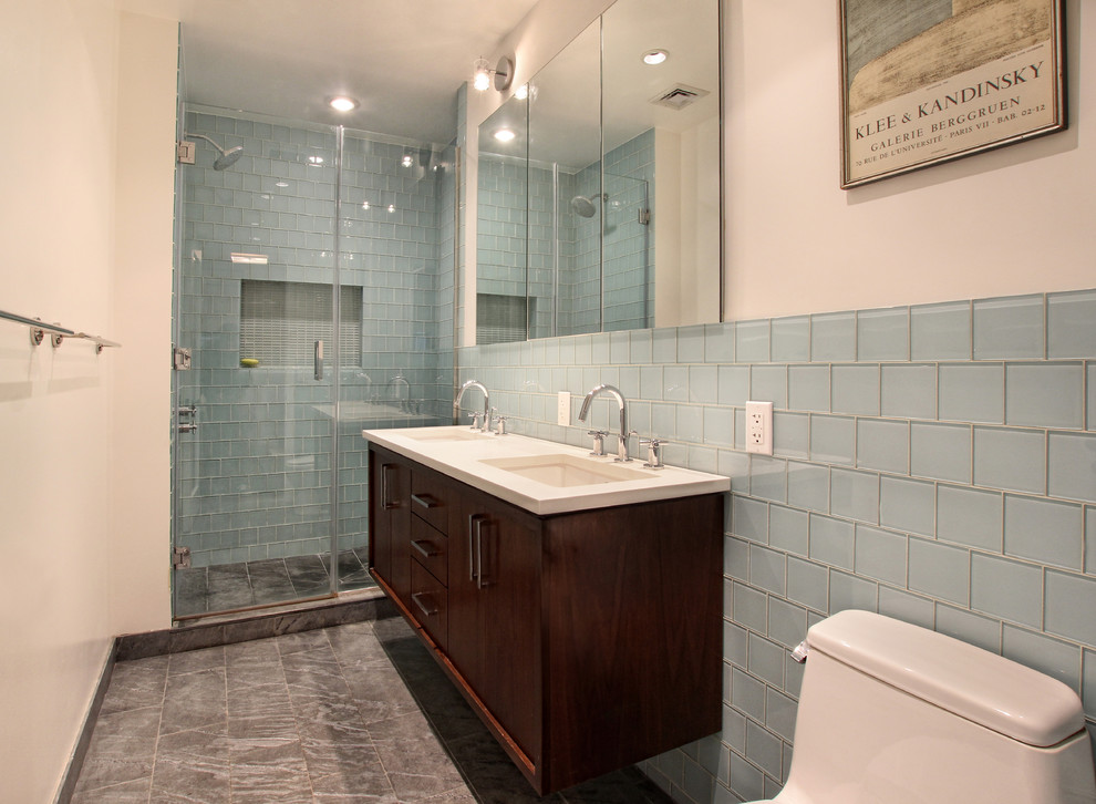 Small contemporary master bathroom in New York with flat-panel cabinets, dark wood cabinets, an alcove shower, a one-piece toilet, blue tile, glass tile, white walls, slate floors, an undermount sink and solid surface benchtops.