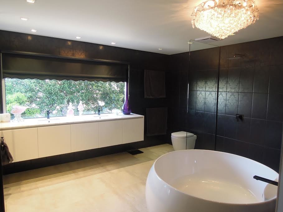 This is an example of a modern master bathroom in Melbourne with a freestanding tub, a one-piece toilet, ceramic tile, an integrated sink, an open shower, recessed-panel cabinets, white cabinets, a double shower, black tile, porcelain floors, marble benchtops and white benchtops.