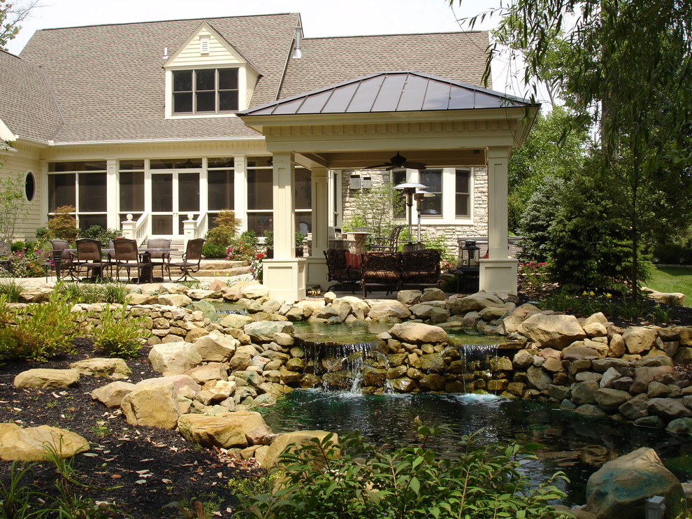 Foto di un patio o portico di medie dimensioni e dietro casa con fontane, pavimentazioni in pietra naturale e una pergola