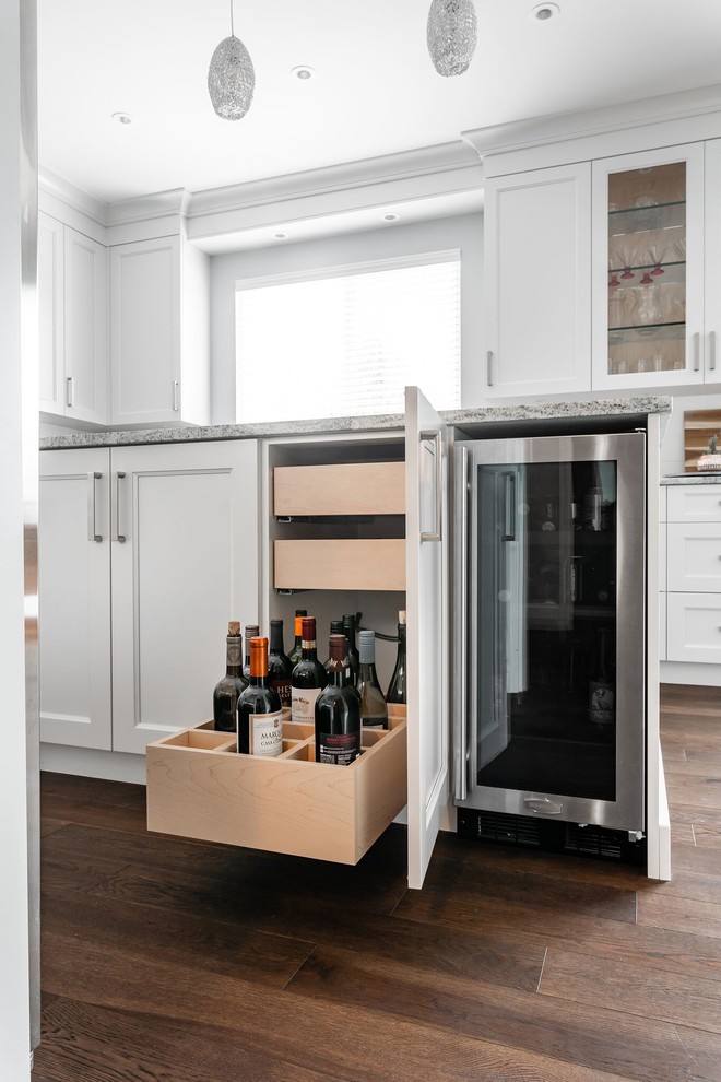 Large transitional u-shaped medium tone wood floor and brown floor eat-in kitchen photo in Vancouver with an undermount sink, recessed-panel cabinets, white cabinets, granite countertops, white backsplash, subway tile backsplash, stainless steel appliances, an island and multicolored countertops