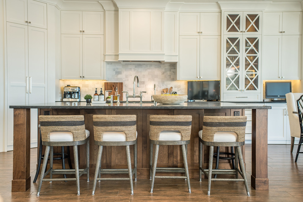 Large beach style eat-in kitchen in Orlando with shaker cabinets, white splashback, medium hardwood floors, with island, brown floor, beige cabinets, marble splashback and grey benchtop.
