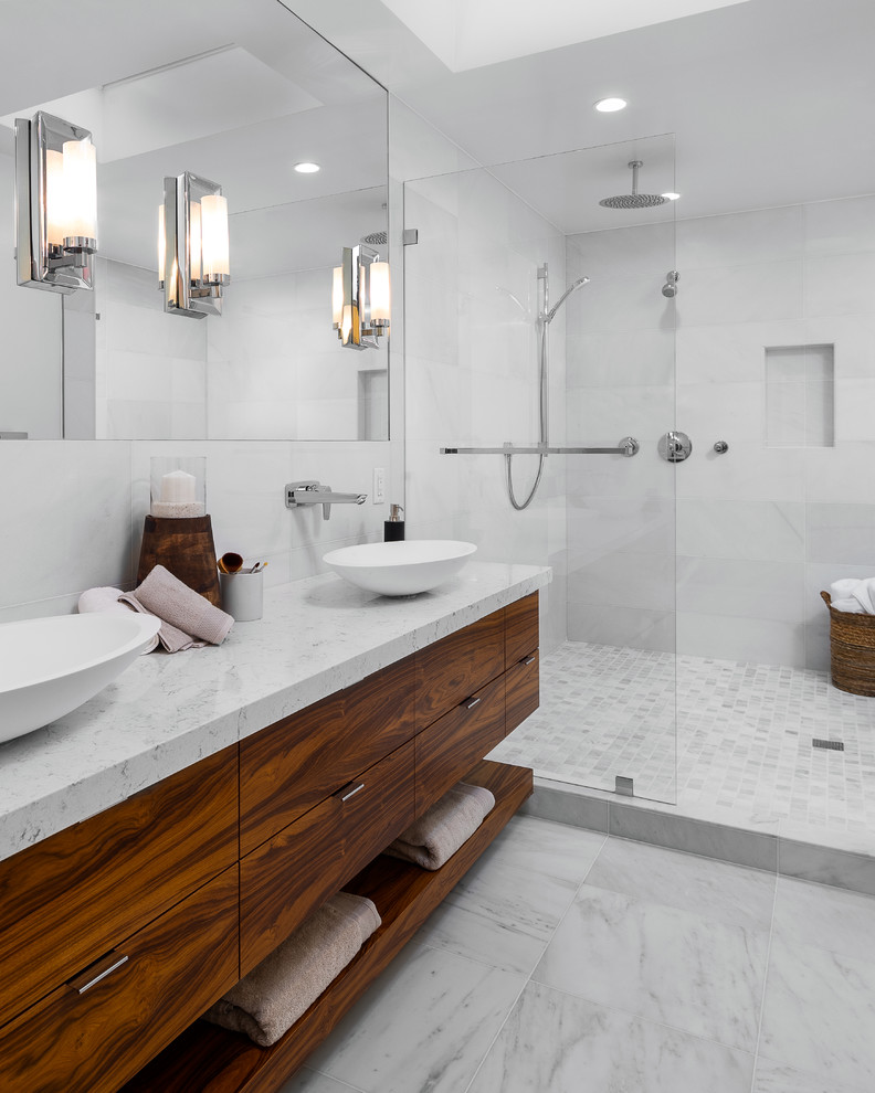 Inspiration for a contemporary master bathroom in Los Angeles with flat-panel cabinets, medium wood cabinets, a freestanding tub, an open shower, a wall-mount toilet, white tile, marble, white walls, marble floors, a vessel sink, marble benchtops, white floor, an open shower and white benchtops.