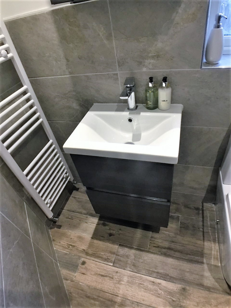 Inspiration for a mid-sized modern master bathroom in Other with flat-panel cabinets, a curbless shower, a two-piece toilet, gray tile, porcelain tile, laminate floors, a drop-in sink, brown floor, a single vanity and a floating vanity.