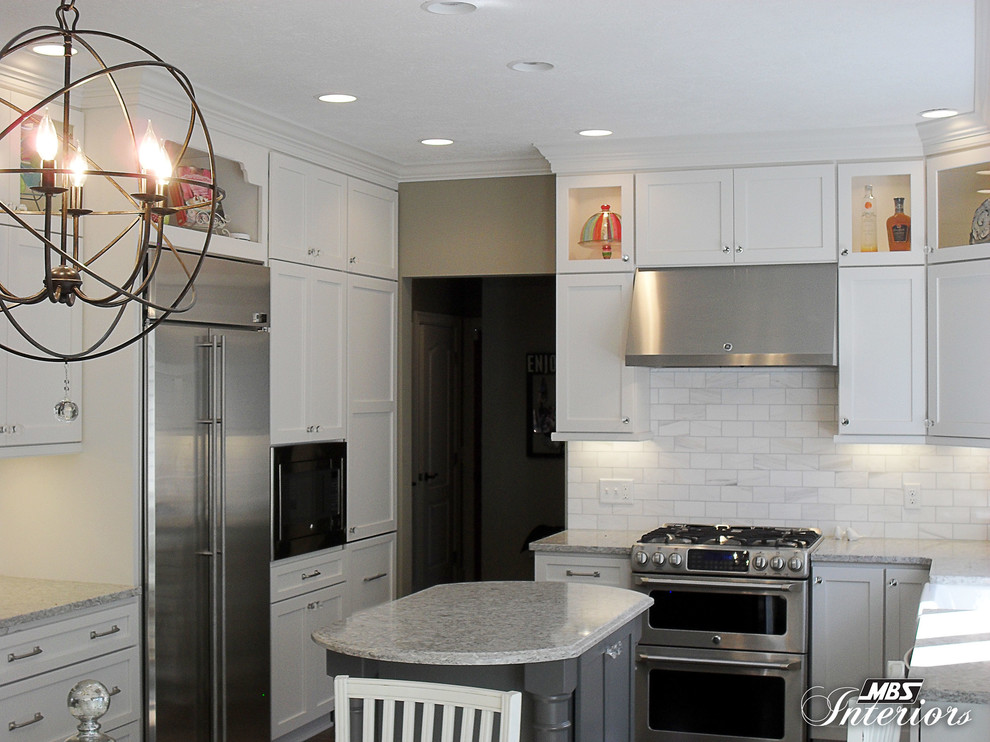 Inspiration for a mid-sized transitional u-shaped medium tone wood floor eat-in kitchen remodel with a farmhouse sink, shaker cabinets, white cabinets, quartzite countertops, white backsplash, subway tile backsplash, stainless steel appliances and an island