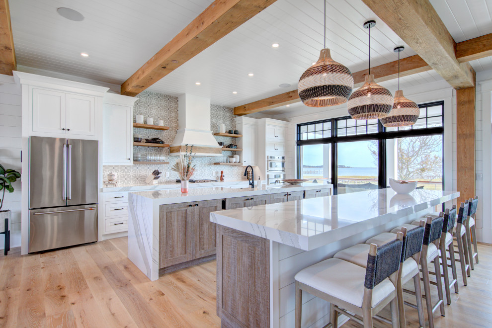 Photo of an expansive country kitchen in Other with a farmhouse sink, shaker cabinets, quartzite benchtops, porcelain splashback, stainless steel appliances, multiple islands, white benchtop, exposed beam, white cabinets, multi-coloured splashback and light hardwood floors.