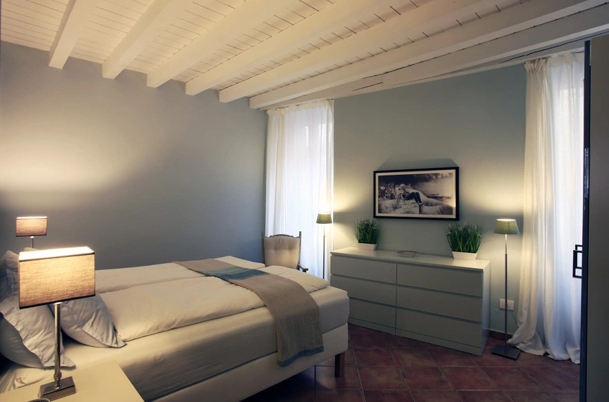 This is an example of a small contemporary master bedroom with terracotta flooring and exposed beams.