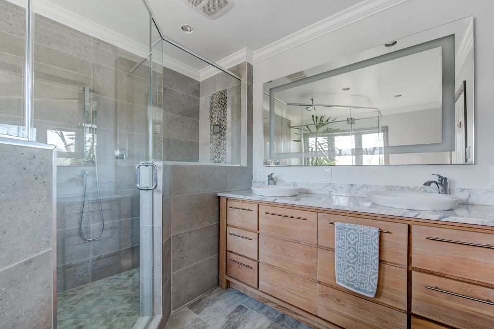 Photo of a mid-sized contemporary bathroom in DC Metro with flat-panel cabinets, medium wood cabinets, an alcove shower, gray tile, grey walls, a vessel sink, multi-coloured floor, a hinged shower door and multi-coloured benchtops.