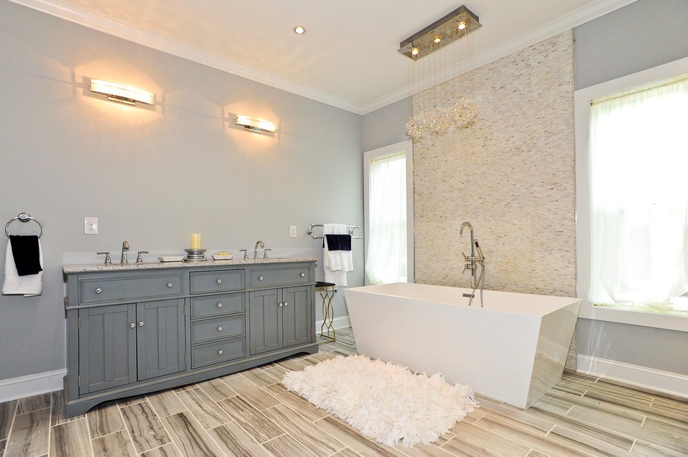 Freestanding bathtub - mid-sized transitional porcelain tile freestanding bathtub idea in Nashville with beaded inset cabinets, gray cabinets, gray walls, quartz countertops and an undermount sink