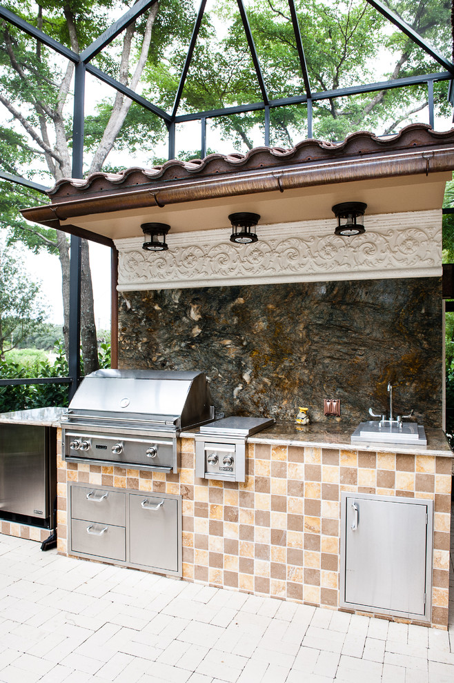 This is an example of a mid-sized tropical backyard patio in Miami with an outdoor kitchen and brick pavers.