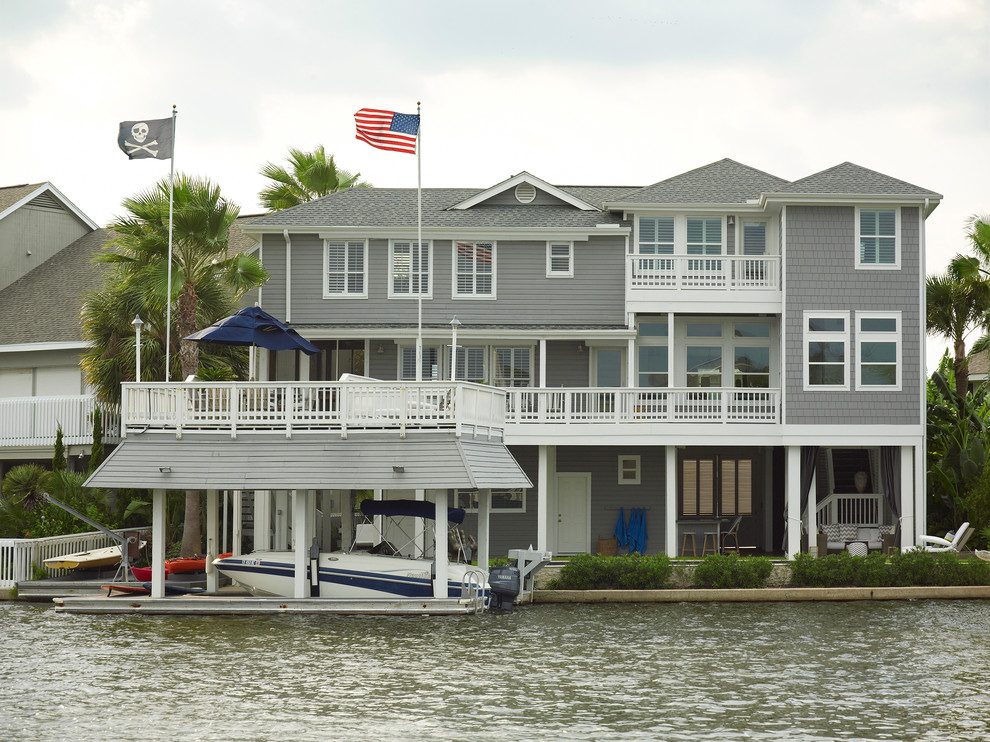 This is an example of an expansive beach style three-storey grey exterior in Houston with wood siding and a hip roof.