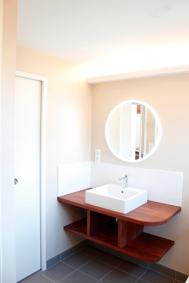 This is an example of a mid-sized modern master bathroom in Other with open cabinets, medium wood cabinets, white tile, beige walls, ceramic floors, a drop-in sink, wood benchtops, grey floor, a drop-in tub, a curbless shower, a wall-mount toilet, ceramic tile, a hinged shower door, brown benchtops, a niche, a floating vanity, coffered and a single vanity.