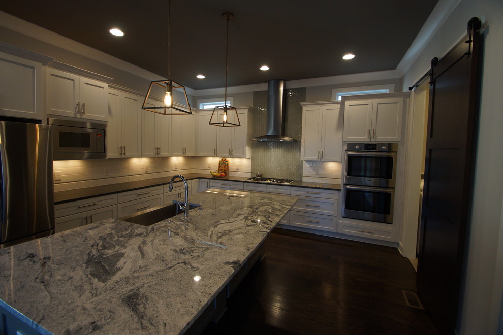 Large transitional dark wood floor kitchen photo in Nashville with an undermount sink, white cabinets, granite countertops, white backsplash and stainless steel appliances