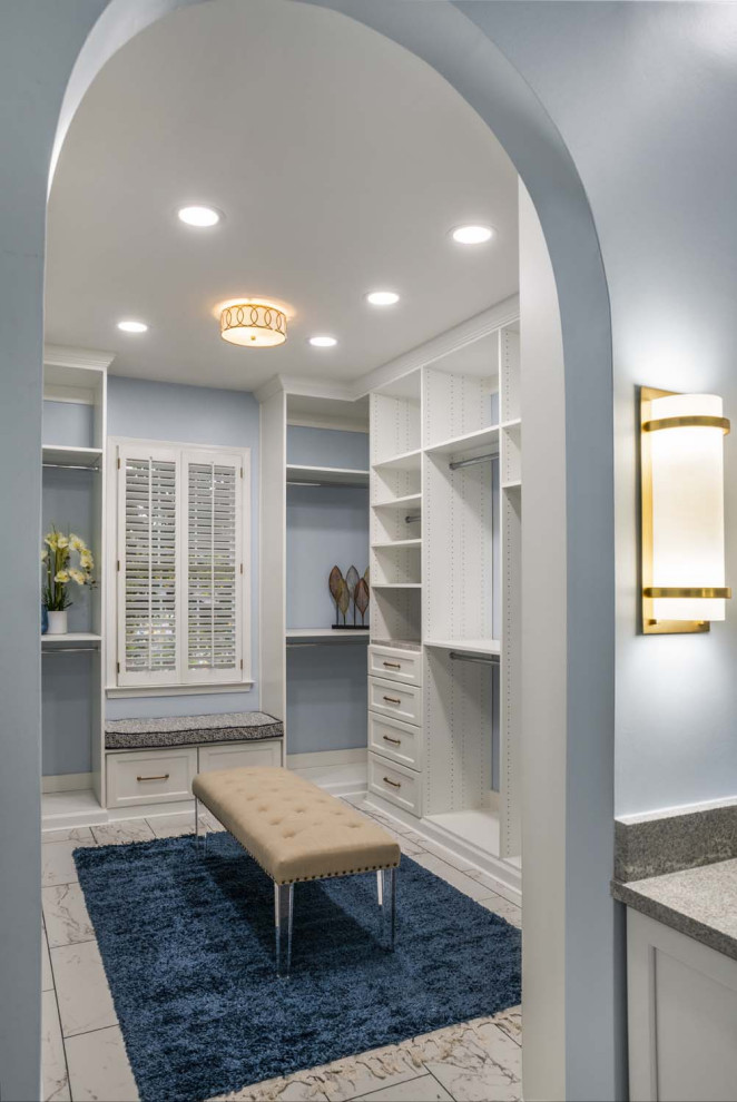 Large transitional gender-neutral walk-in wardrobe in Atlanta with recessed-panel cabinets, white cabinets, ceramic floors and white floor.