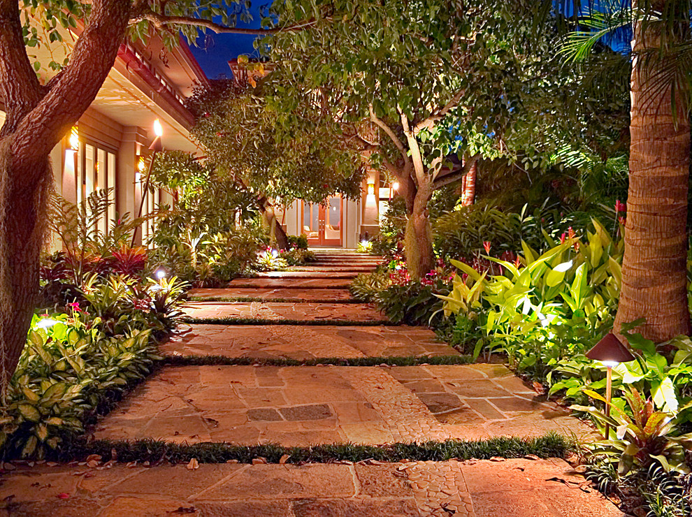 Large tropical front yard formal garden in Hawaii with a garden path and natural stone pavers.