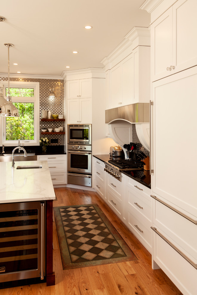 Inspiration for a mid-sized transitional l-shaped enclosed kitchen remodel with shaker cabinets, white cabinets, stainless steel appliances, an island and white countertops