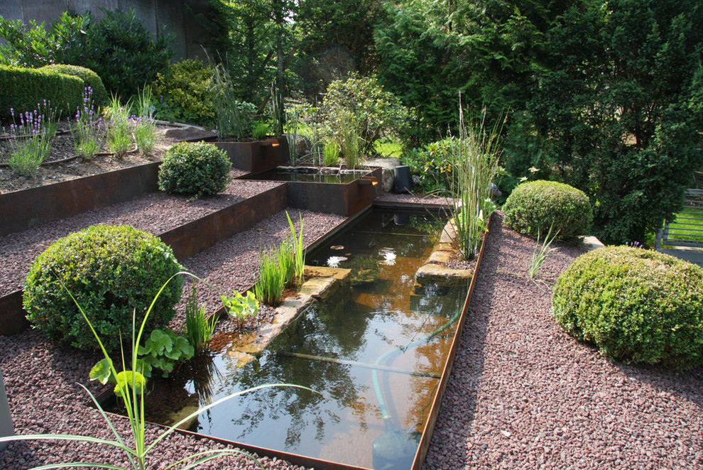 Large traditional sloped full sun xeriscape in Stuttgart with a water feature and gravel for summer.