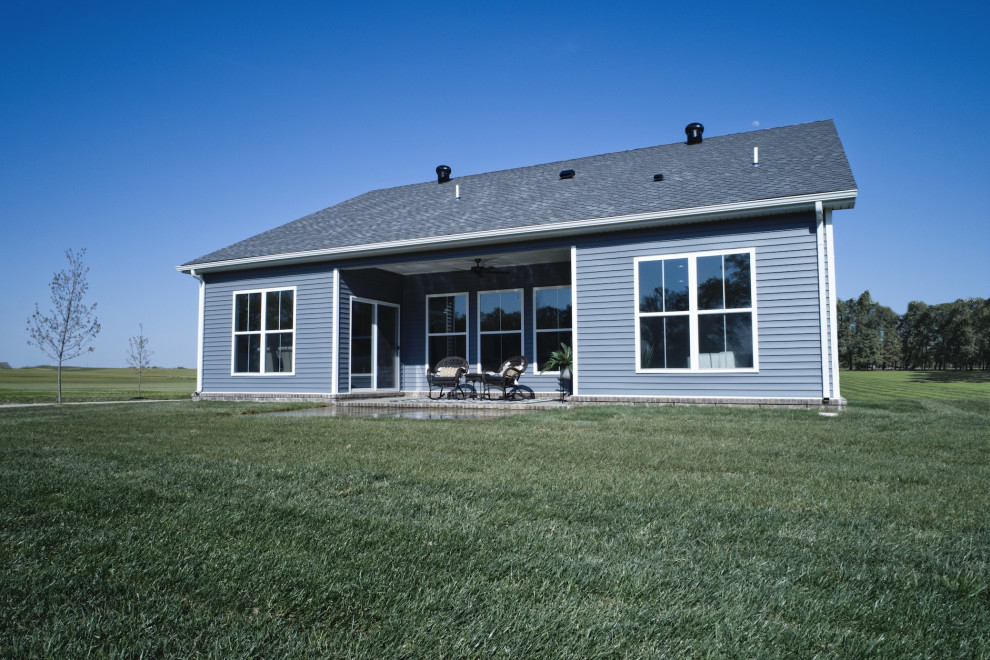 Idées déco pour une façade de maison bleue campagne en planches et couvre-joints de taille moyenne et de plain-pied avec un revêtement en vinyle, un toit à quatre pans, un toit en shingle et un toit gris.