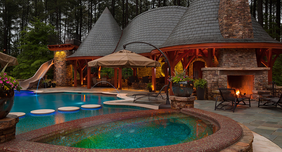 Large eclectic backyard custom-shaped pool in Raleigh with a water slide and natural stone pavers.
