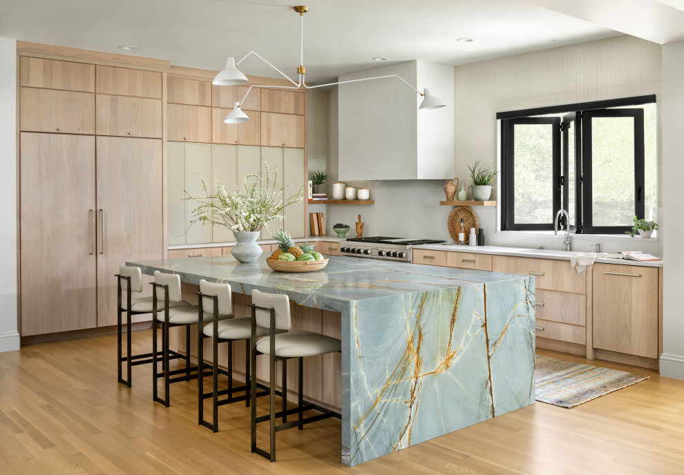 Photo of a transitional l-shaped kitchen in Denver with flat-panel cabinets, light wood cabinets, stainless steel appliances, light hardwood floors, with island, beige floor and white benchtop.