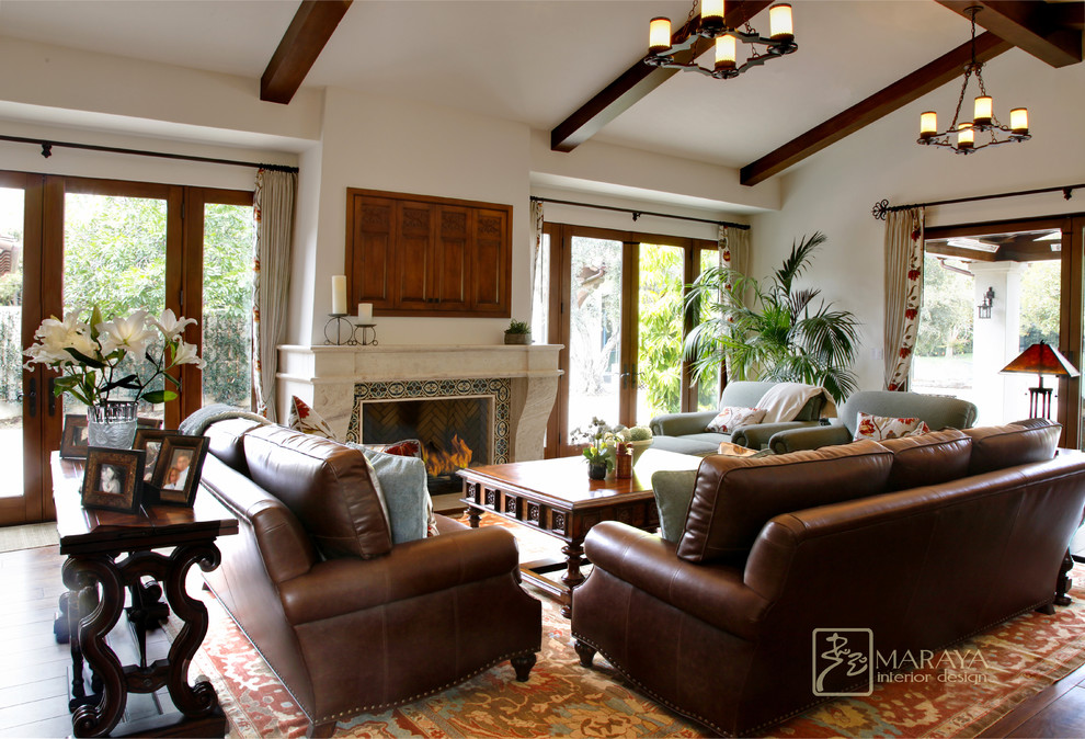 Example of a large tuscan formal and open concept dark wood floor living room design in Other with white walls, a standard fireplace, a stone fireplace and a concealed tv