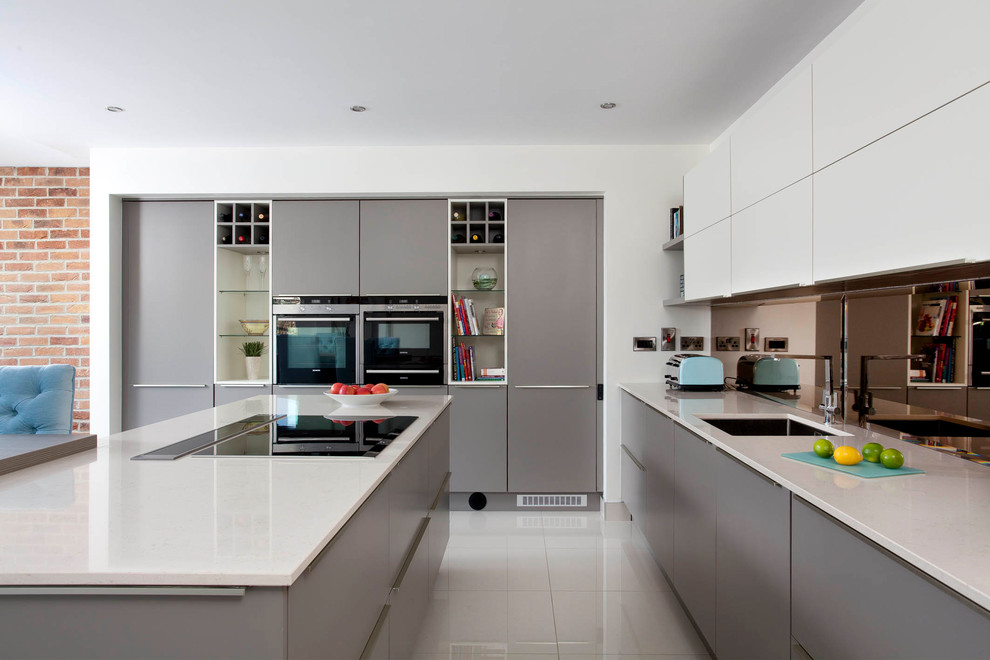 Design ideas for a mid-sized contemporary u-shaped open plan kitchen in Dublin with an integrated sink, flat-panel cabinets, grey cabinets, quartzite benchtops, grey splashback, glass sheet splashback, black appliances and with island.