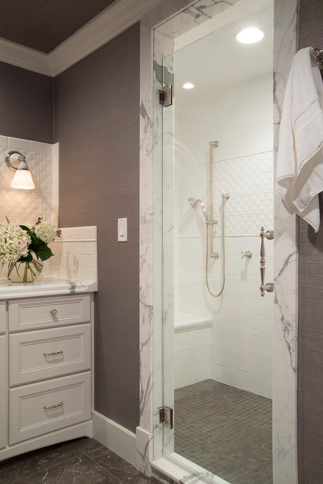 Design ideas for a mid-sized transitional master bathroom in St Louis with recessed-panel cabinets, white cabinets, a freestanding tub, gray tile, subway tile, grey walls, porcelain floors, an undermount sink and marble benchtops.