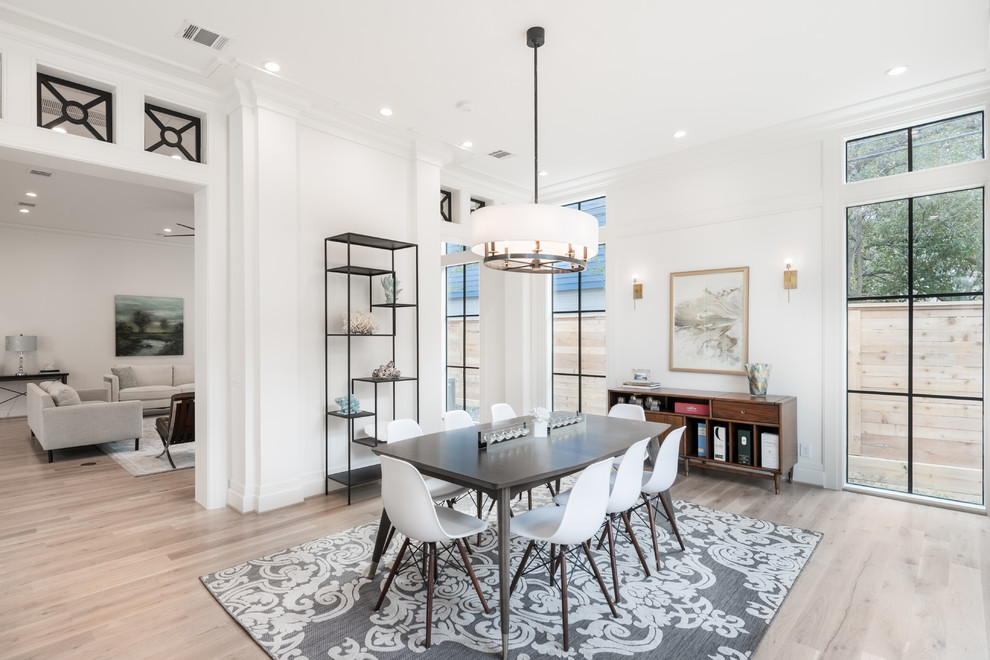 Example of a transitional light wood floor and beige floor enclosed dining room design in Houston with white walls