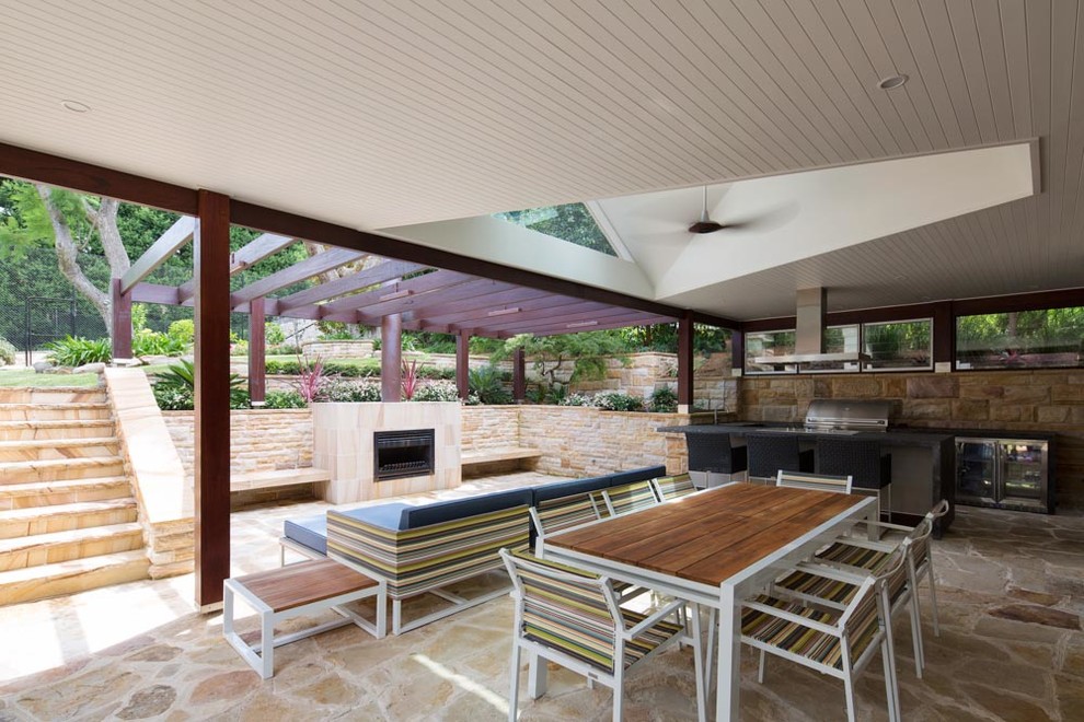 This is an example of a contemporary backyard patio in Sydney with a water feature, natural stone pavers and a roof extension.