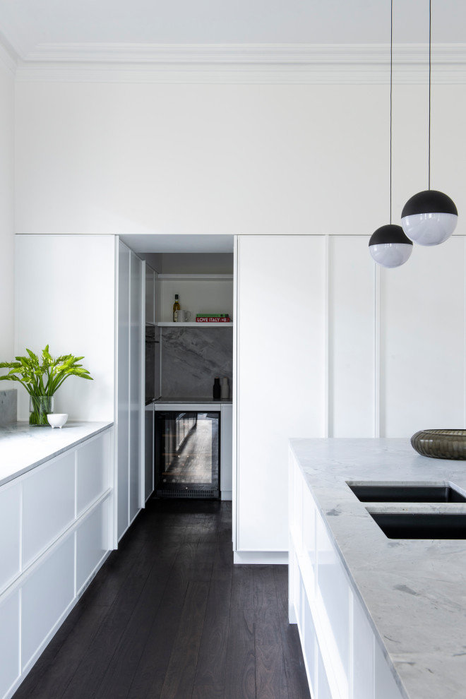 Inspiration for a large contemporary l-shaped kitchen pantry in Sydney with an undermount sink, shaker cabinets, white cabinets, marble benchtops, white splashback, stone slab splashback, black appliances, dark hardwood floors, with island and white benchtop.
