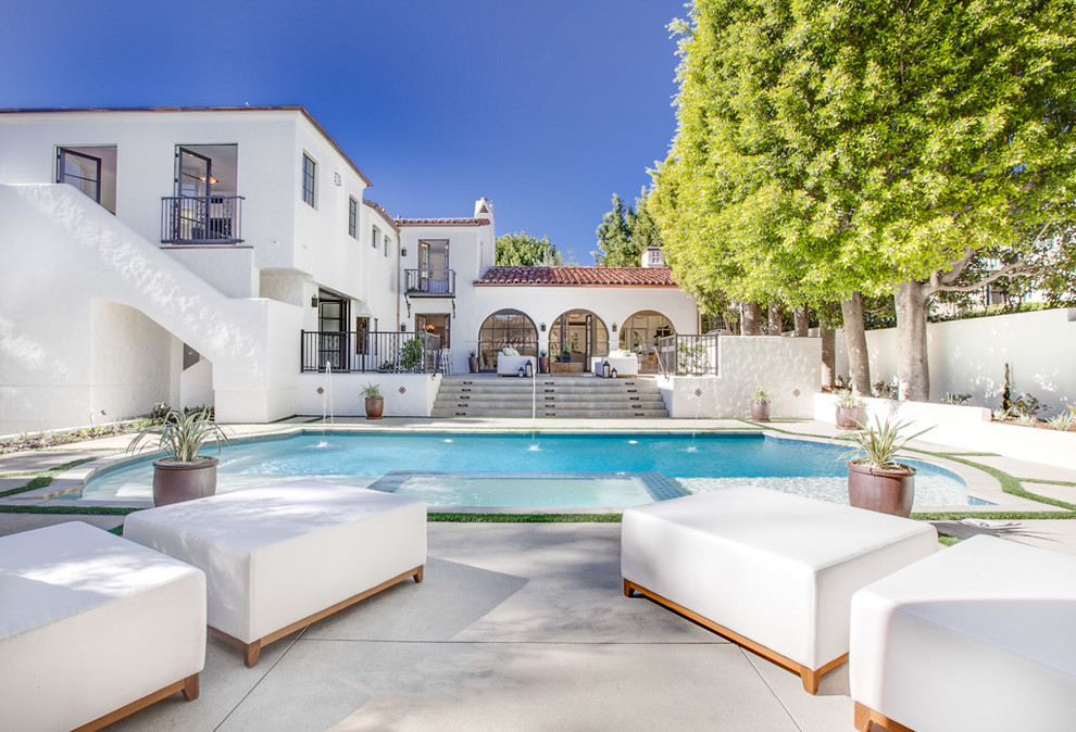 Photo of a large mediterranean backyard pool in Los Angeles with a water feature.