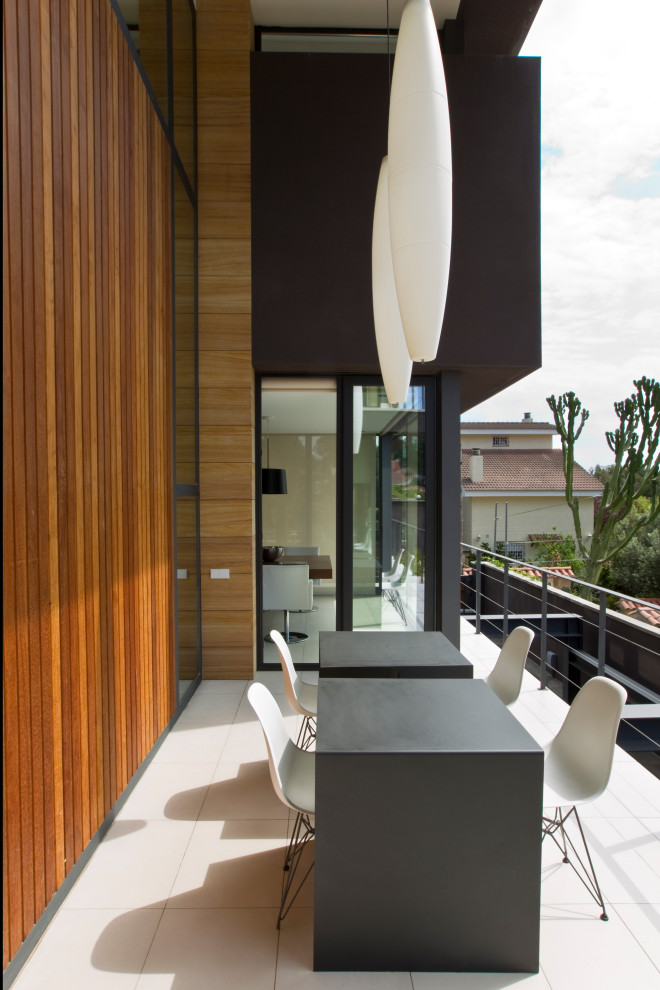 Mid-sized contemporary balcony in Other with a roof extension and metal railing.
