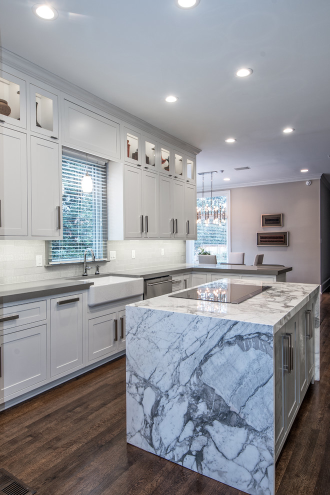 Enclosed kitchen - large transitional l-shaped dark wood floor enclosed kitchen idea with a farmhouse sink, shaker cabinets, white cabinets, solid surface countertops, white backsplash, subway tile backsplash, stainless steel appliances and an island