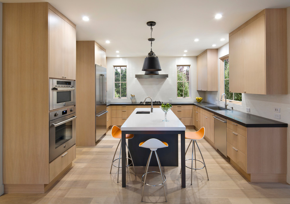 Design ideas for a contemporary u-shaped kitchen in San Francisco with an undermount sink, flat-panel cabinets, light wood cabinets, stainless steel appliances, light hardwood floors and with island.