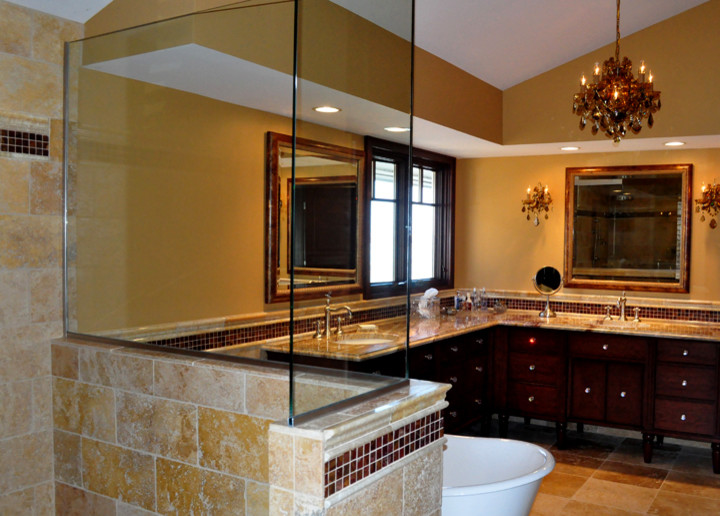 Photo of a large traditional master bathroom in Minneapolis with dark wood cabinets, a freestanding tub, a corner shower, brown tile, stone tile, brown walls, travertine floors, an undermount sink, beige floor, a hinged shower door and granite benchtops.