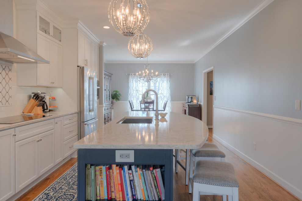 Example of a mid-sized transitional galley medium tone wood floor eat-in kitchen design with an undermount sink, flat-panel cabinets, white cabinets, quartz countertops, white backsplash, subway tile backsplash, stainless steel appliances, an island and white countertops
