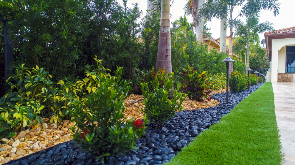 Large traditional backyard partial sun xeriscape in Miami with with lawn edging and natural stone pavers.