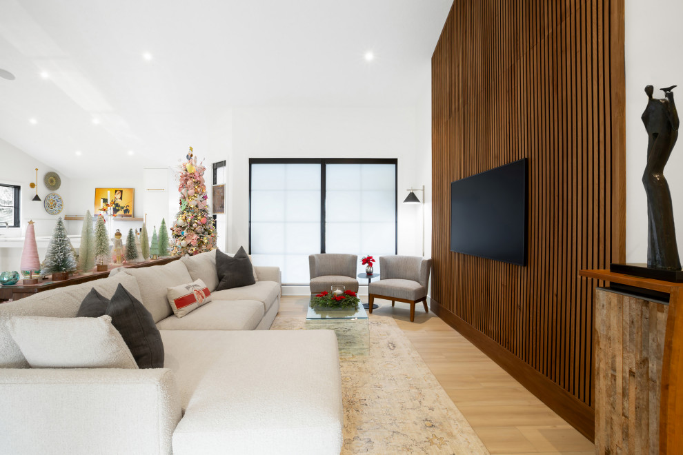 На фото: открытая гостиная комната в современном стиле с белыми стенами, светлым паркетным полом, телевизором на стене, сводчатым потолком и деревянными стенами с