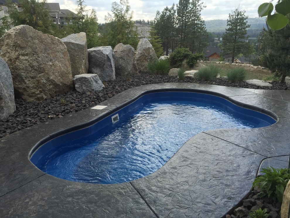 Photo of a small tropical backyard kidney-shaped pool in Seattle with a hot tub and stamped concrete.