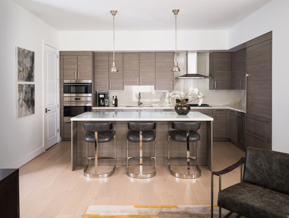 This is an example of a contemporary l-shaped open plan kitchen in Houston with flat-panel cabinets, light hardwood floors, with island, beige floor, white benchtop, an undermount sink, dark wood cabinets, beige splashback, stainless steel appliances, quartz benchtops and stone slab splashback.