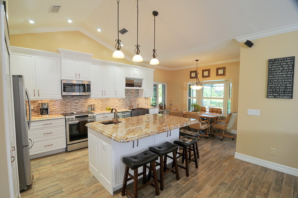 Eat-in kitchen - transitional medium tone wood floor and multicolored floor eat-in kitchen idea in Miami with a farmhouse sink, raised-panel cabinets, white cabinets, granite countertops, multicolored backsplash, ceramic backsplash, stainless steel appliances and an island