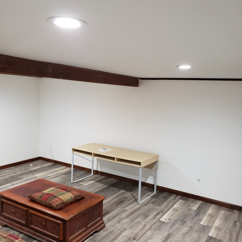 Photo of a mid-sized arts and crafts fully buried basement in Other with white walls, vinyl floors, no fireplace, grey floor, coffered and brick walls.