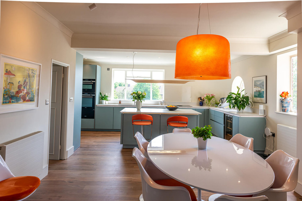 Immagine di una cucina minimalista di medie dimensioni con lavello integrato, ante a filo, ante blu, top in quarzite, elettrodomestici neri e top bianco