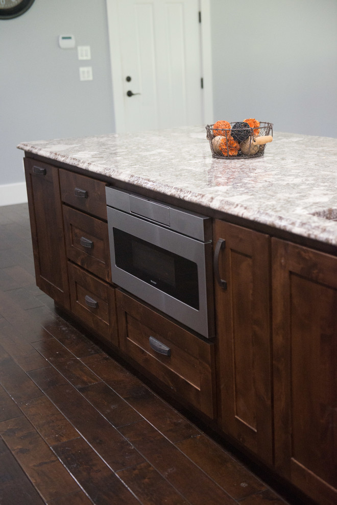 Example of a transitional l-shaped open concept kitchen design with an undermount sink, shaker cabinets, dark wood cabinets, granite countertops, stainless steel appliances, an island and multicolored countertops