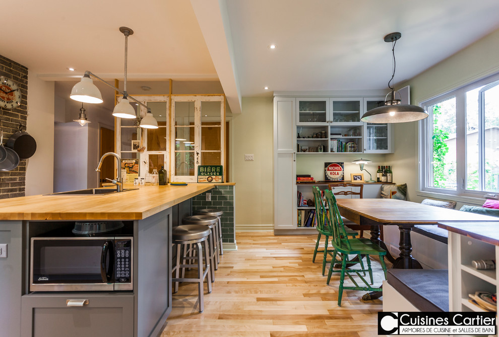 Open concept kitchen - large transitional galley medium tone wood floor open concept kitchen idea in Montreal with a single-bowl sink, shaker cabinets, gray cabinets, wood countertops, green backsplash, ceramic backsplash, white appliances and an island