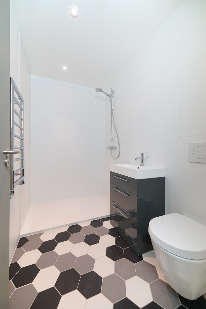 Small contemporary 3/4 bathroom in London with flat-panel cabinets, grey cabinets, an open shower, white tile, ceramic tile, ceramic floors, grey floor, an open shower, a single vanity and a freestanding vanity.