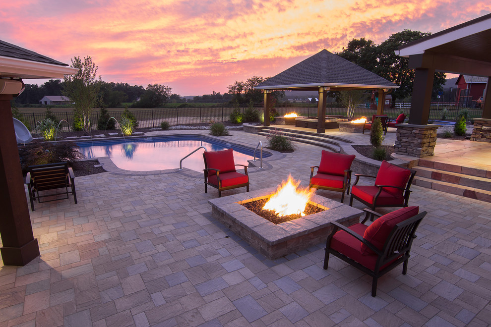 Large contemporary backyard l-shaped lap pool in Other with a hot tub and concrete pavers.