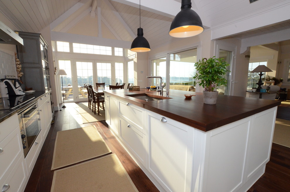 Inspiration for a mid-sized traditional single-wall open plan kitchen in Other with a single-bowl sink, beaded inset cabinets, white cabinets, wood benchtops, white splashback, porcelain splashback, white appliances, dark hardwood floors and with island.